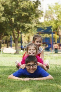 Happy children of three playing piggy back at summer camp