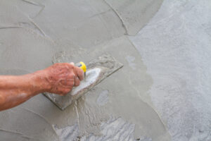 Hand using trowel on fresh concrete in construction site